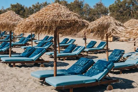 Empty sun beds under the umbrellas on a beach in Mykonos, Greece. Stock Photos