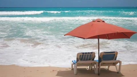 Empty sun loungers under the red parasol on the sandy beach near the sea water Video stock 272509848
