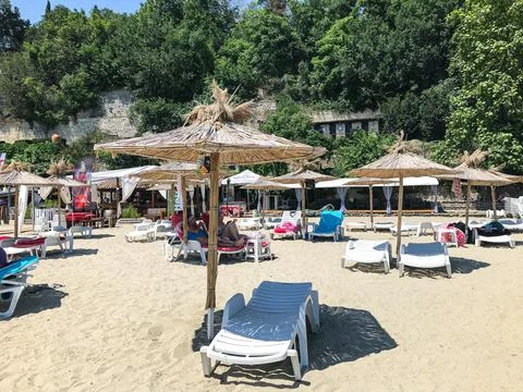 An empty sunbed with an umbrella on a sandy beach. Balchik. Bulgaria. Stock Photos