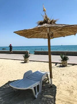 An empty sunbed with an umbrella on a sandy beach. Balchik. Bulgaria. Stock Photos