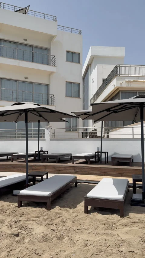 Empty sunbeds and beach umbrellas on sand near modern white luxury resort hotel Stock Footage 346312795