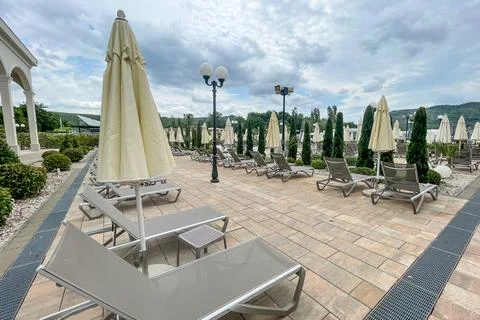 Empty sunbeds and umbrellas on pool terrace at spa resort exterior on cloud.. Fotos de archivo