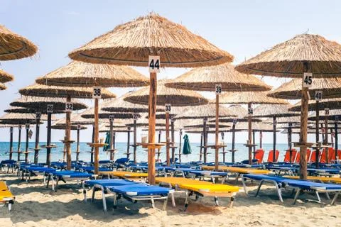 Empty Sunchair Deckchairs On Beach Under Parasols, Overlooking The Blue Sea I Fotos de archivo