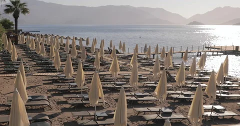 Empty Sunset Beach chairs and sun umbrellas await tourists. Beautiful seashore  Stock Footage 154335585