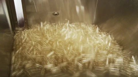 Empty Supplement Capsules being fed into a Production Machine Stock Footage 50029759