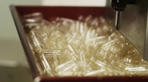 Empty Supplement Capsules being fed into a Production Machine Stock Footage 50030303