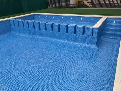 Empty swimming pool with blue mosaic tiles and steps Foto stock