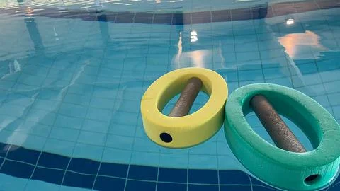 An empty swimming pool with Styrofoam exercise equipment floating in it. Stock Photos