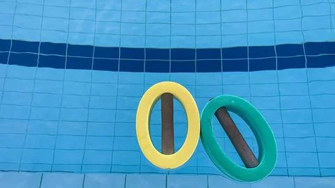 An empty swimming pool with Styrofoam exercise equipment floating in it. Stock Photos