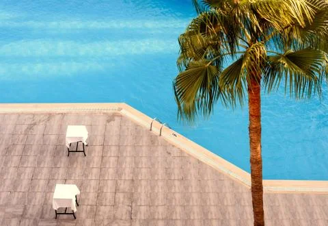 Empty swimming pool with two empty seats and a palm tree - taken from an elev Stock Photos