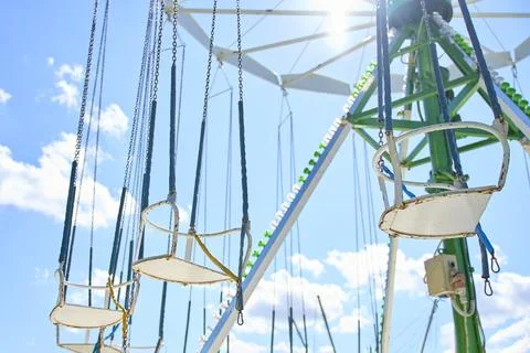 Empty swing carousel seats hanging from chains against blue sky Stock Photos