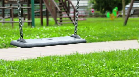 Empty swing with chains swaying at playground for child, moved from wind, on Stock Footage 56613239