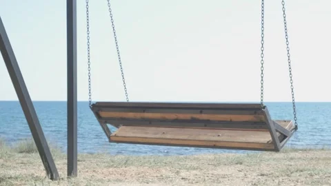 Empty swing on chains swings against background of sea Video stock 313891501