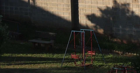 Empty Swing In A Children's Playground, Dramatic Shadow Stock Footage 75555949