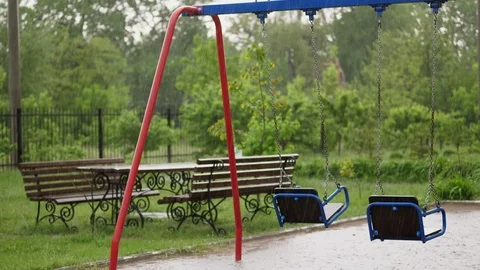 Empty swing drenches in the rain, swaying in wind. a heavy rain, a thunderstorm Stock Footage 90873790