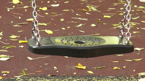 Empty swing moving on the playground, autumn leaves, fall season Stock Footage 32048524