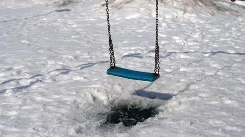 Empty swing moving slowly over melting snow Stock Footage 331803118