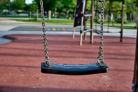 Empty swing at a playground during daylight hours with trees in the backgro.. Stock Photos
