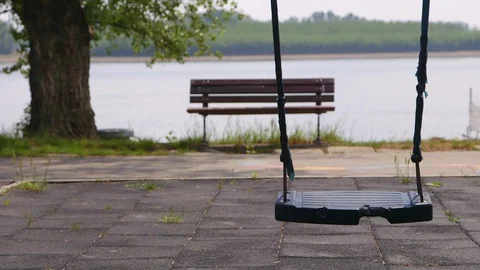 Empty swing from the playground overlooking the water lake river 库存影片 129526174