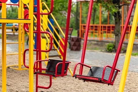 Empty swing at the playground in the rain. Children's swing in the park, wood Фото