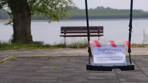 Empty swing with red and white precautionary tape to prevent the spread of co 库存影片 129526168