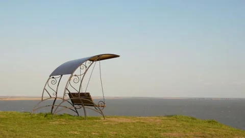 An empty swing on the seashore is rocked by the wind Stock Footage 154439569