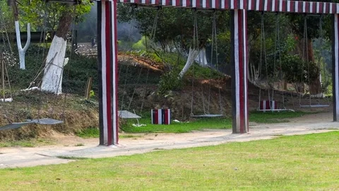 Empty swing set in park with trees and pathway Stock Footage 332611703