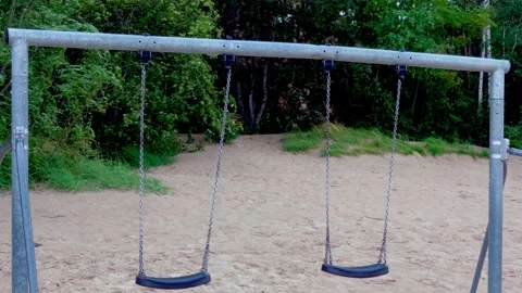 Empty swing set on sandy beach against green pine forest in Jurmala Latvia Video stock 344356005