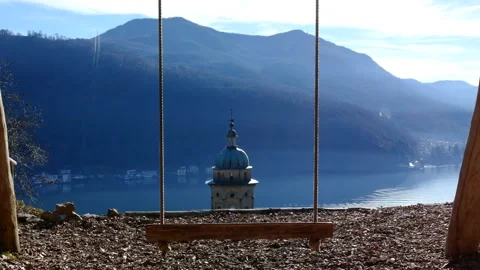 Empty Swing with Sunlight and Mountain View with a Church Tower Vídeo Stock 194012030