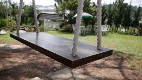 Empty swing sways in an abandoned garden. The silence evokes a chilling Vídeo Stock 312109277