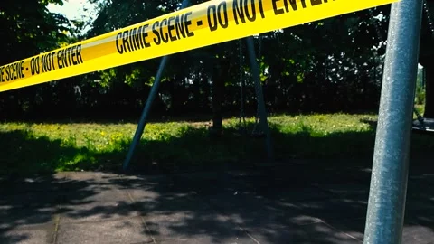 Empty swing swinging behind a yellow crime scene tape during a sunny day at Stock Footage 313117117