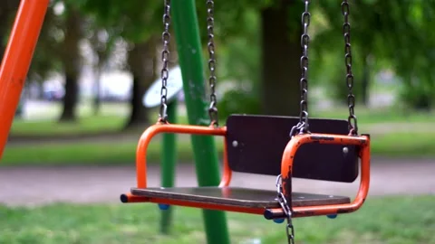 An empty swing swings on chains in a children's park. Close-up Stock Footage 130508049