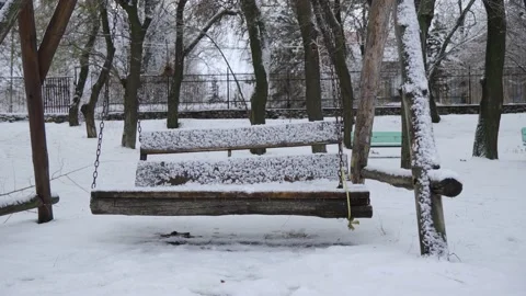 An empty swinging bench in a winter park, strewn with snow. Stock Footage 167955856