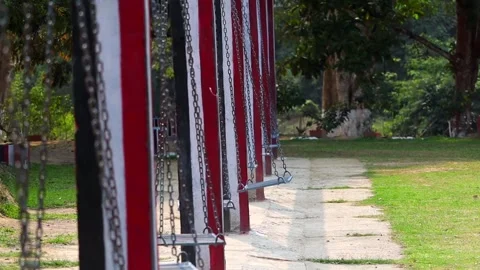 Empty swings aligned in park with striped pillars 스톡 동영상 332611755