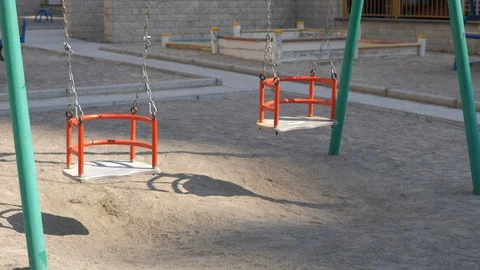 Empty swings on playground swaying in wind Stock Footage 127748860