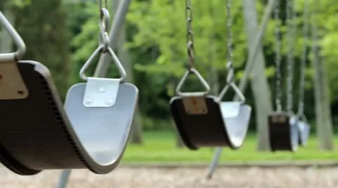 Empty swings swaying at playground Stock Footage
