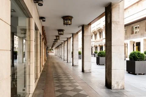 Empty, symmetrical arcade featuring stone columns and decorative lanterns. Stock Photos