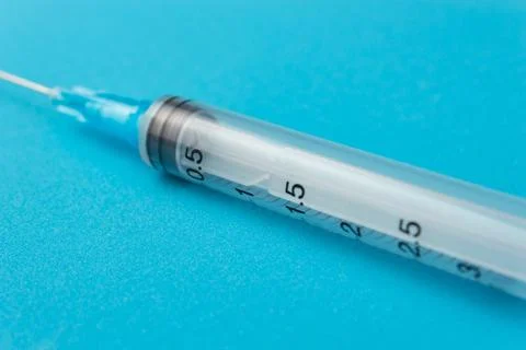 Empty syringe on blue background close up Stock Photos