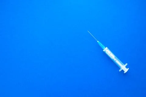 Empty syringe on bright blue background. Health and vaccination concept Stock Photos