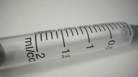 An empty syringe is inscrasyed on a white surface. syringe volume in Stock Footage 141590736