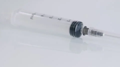 An empty syringe with needles in a protective cap on a white surface. Stock Footage 302172504