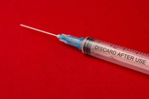 Empty syringe on red background close up Stock Photos