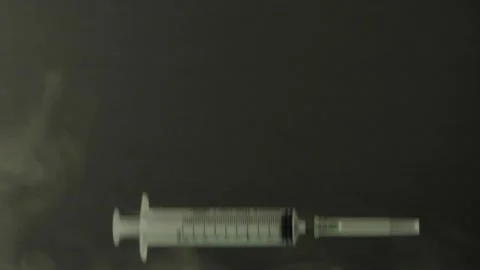 Empty syringes fall in slow motion smoke Stock Footage 156796080