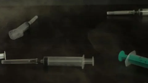 Empty syringes fall on the table in slow motion smoke 2 Stock Footage 156796087