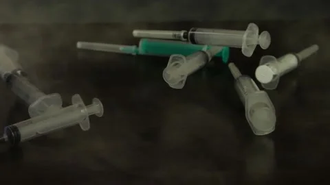 Empty syringes fall on the table in slow motion smoke Stock Footage 156796090