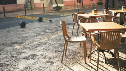 Empty table and chairs in the street cafe illuminated by the sunset light. Copy Stock Footage 246586815