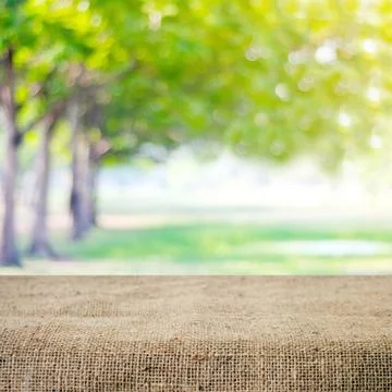 Empty table and sack tablecloth over blur tree with bokeh background, for p.. Stock Photos