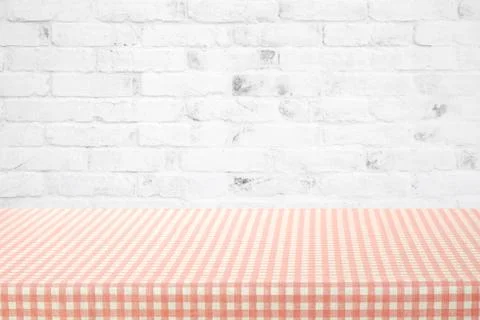 Empty table cover with pink and white tablecloth over white brick wall backgr Stock Photos