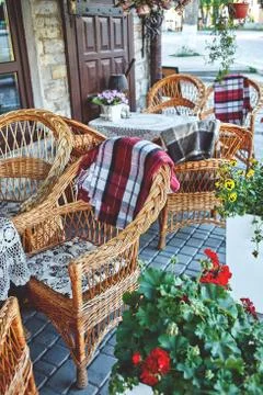 An empty table, flowers and wicker chairs on the street near Cafe Stock Photos