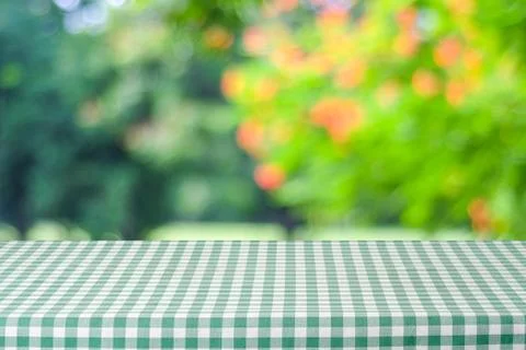 Empty table with green tablecloth over blur garden and bokeh background, fo.. Stock Photos